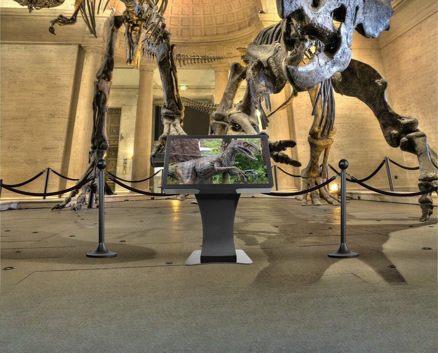 Duraline Angled Kiosk en la sala de un museo, entre esqueletos de dinosaurios
